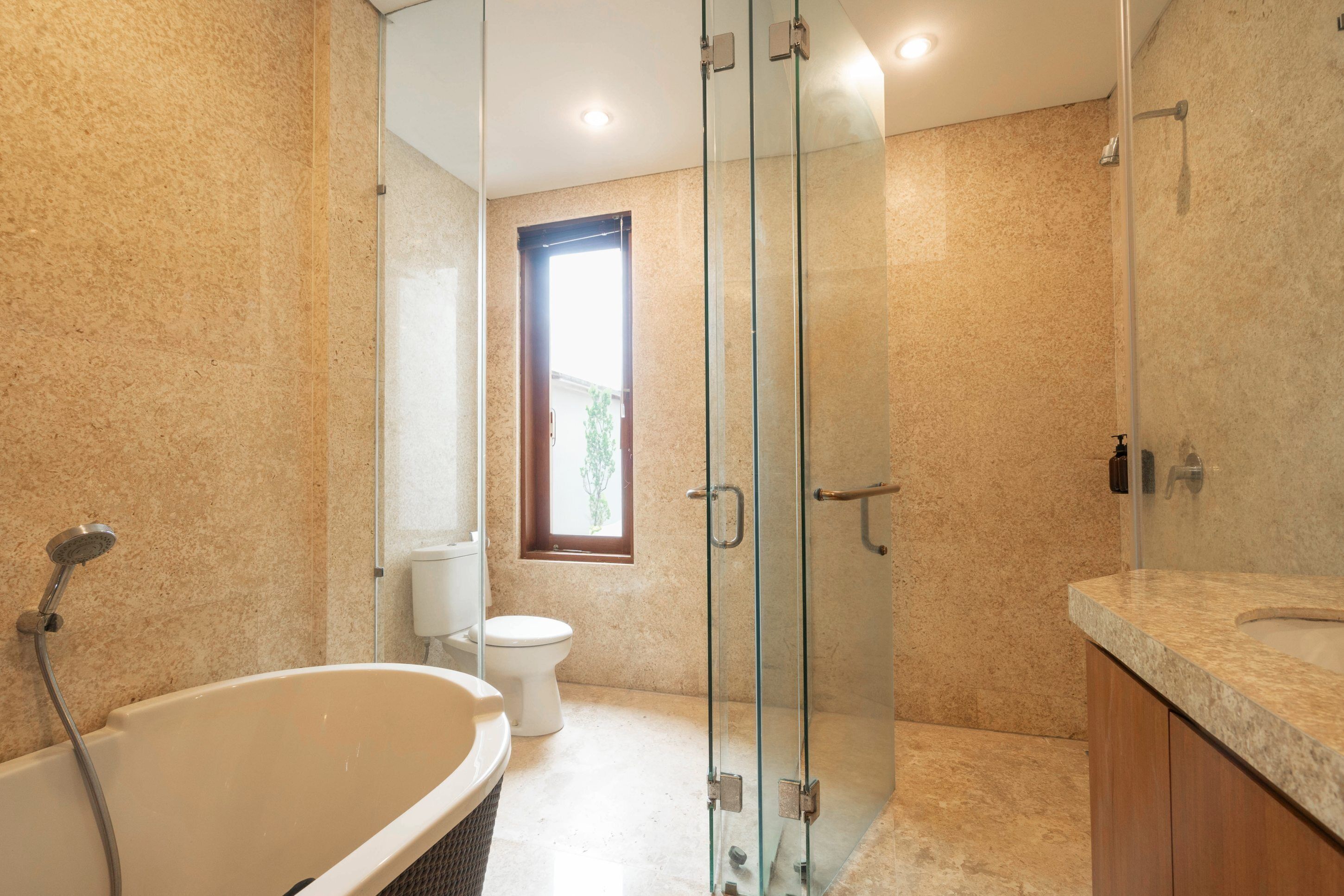 A modern bathroom with a glass-enclosed shower, a freestanding bathtub, and a toilet.