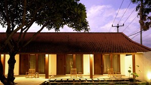 A traditional building with a tiled roof, wooden doors, and a small garden area with a pathway leading to the entrance. - Rarama Living Studio (Kerobokan Kaja)