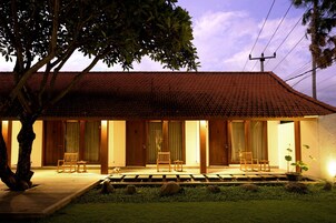 A traditional building with a tiled roof, wooden doors, and a small garden area with a pathway leading to the entrance.