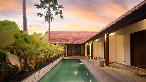 A poolside area with a wooden deck, a tiled roof, and a row of doors. - Rarama Living Studio (Kerobokan Kaja)