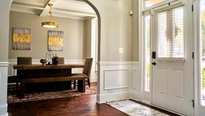Ein Essbereich mit Holztisch und Bank, einer Chandelierleuchtre und zwei abstrakten Bildern an der Wand.