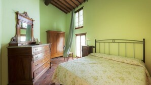 Quarto com cama, penteadeira de madeira e espelho.
