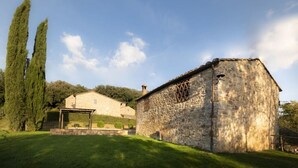 Um edifício de pedra com pérgula e área gramada.