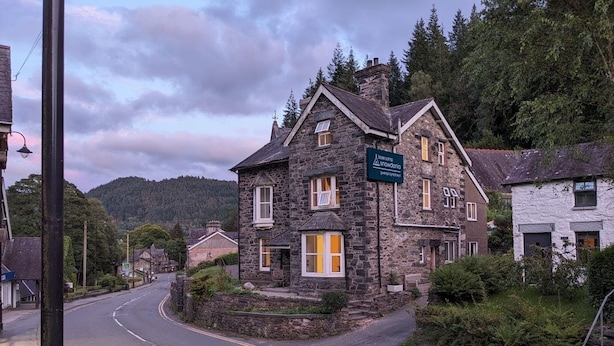 Un edificio de piedra con un cartel que dice "base camp snowdonia" en una calle con una montaña al fondo.