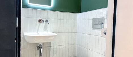 Et badeværelse med en hvid vask, toilet og et spejl.