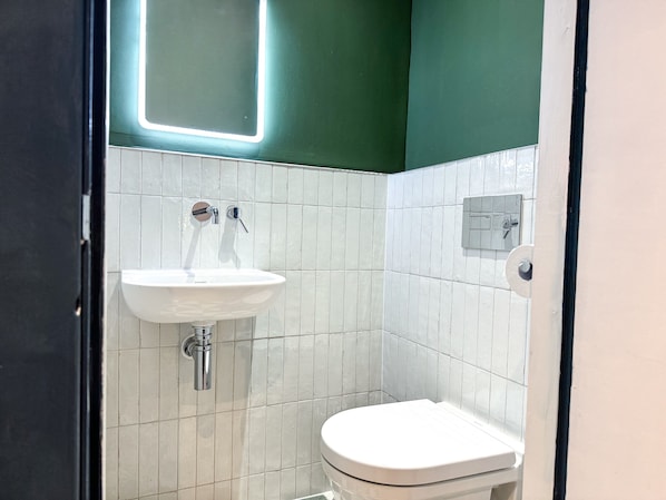 A bathroom with a white sink, a toilet, and a mirror. - Base Camp Snowdonia (Betws-Y-Coed)