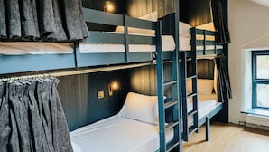 Dormitorio con literas, ventana, paredes de madera y una lámpara.