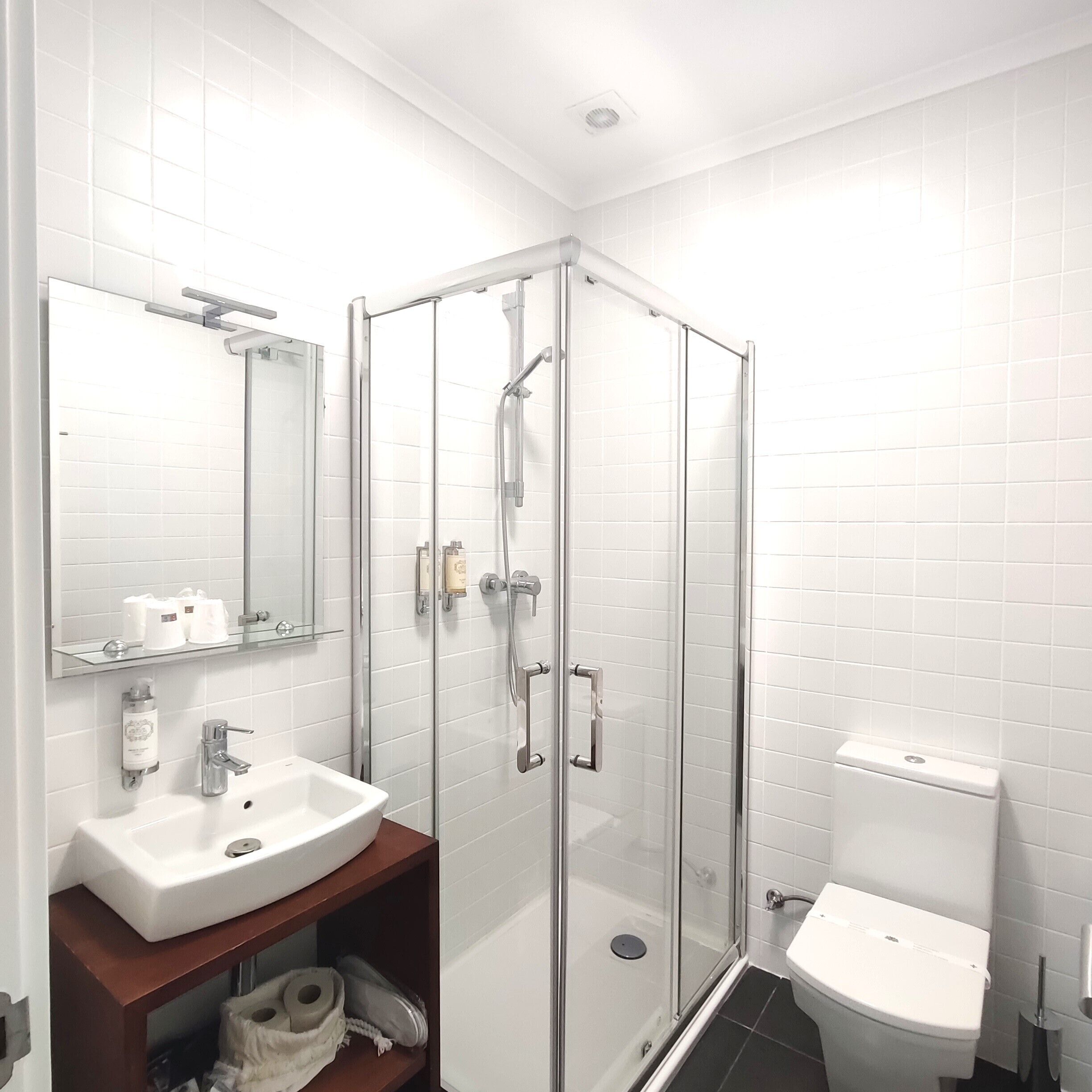 Un baño moderno con ducha de vidrio, lavamanos blanco y retrete.