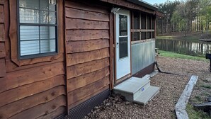 Une cabane en bois avec une fenêtre, une porte et un petit porche.