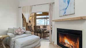 Un salon chaleureux avec une cheminée, un canapé, une table basse et une vue sur la terrasse extérieure.