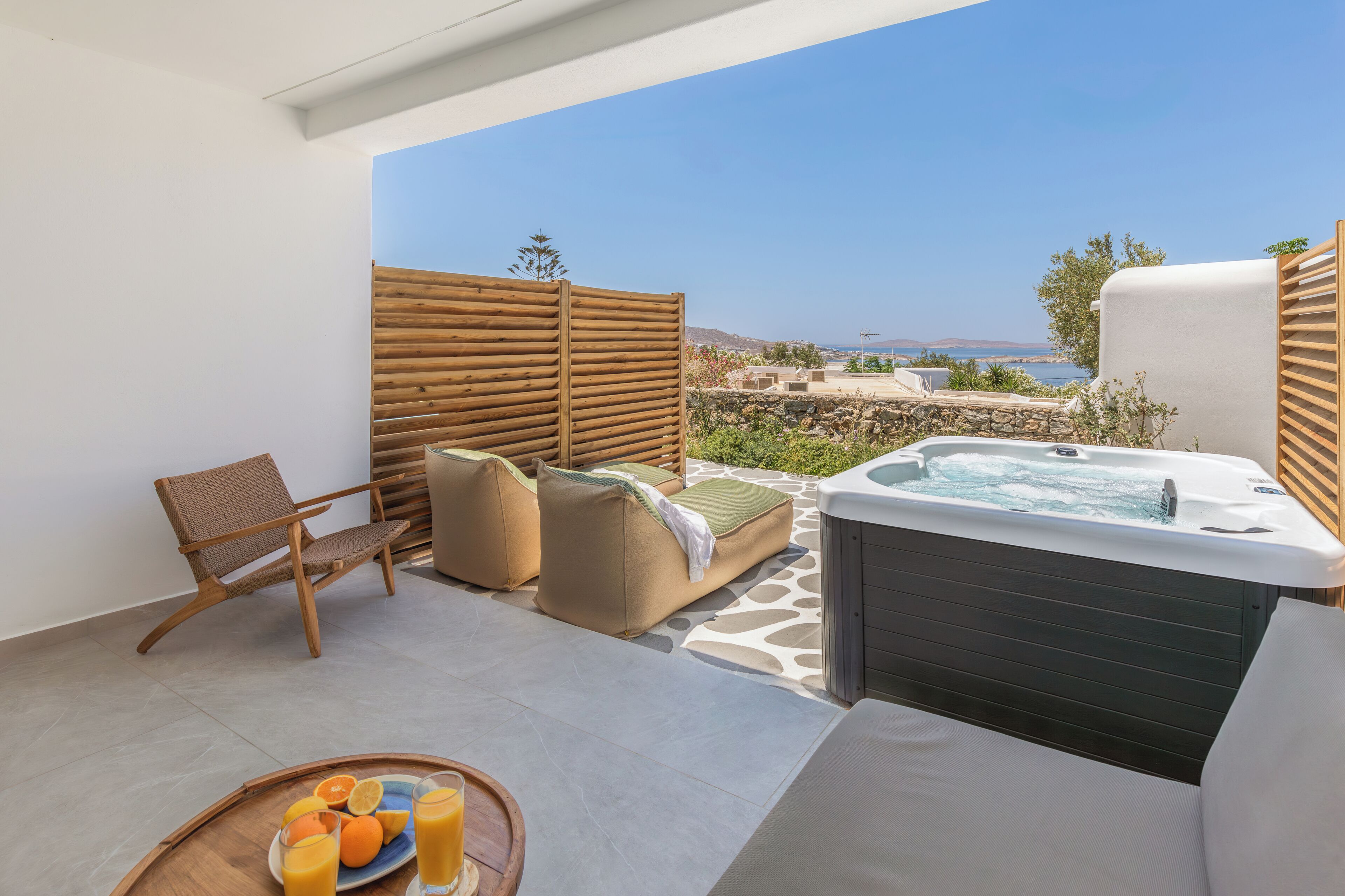A balcony with a hot tub, lounge chairs, and a table with fruit and drinks.