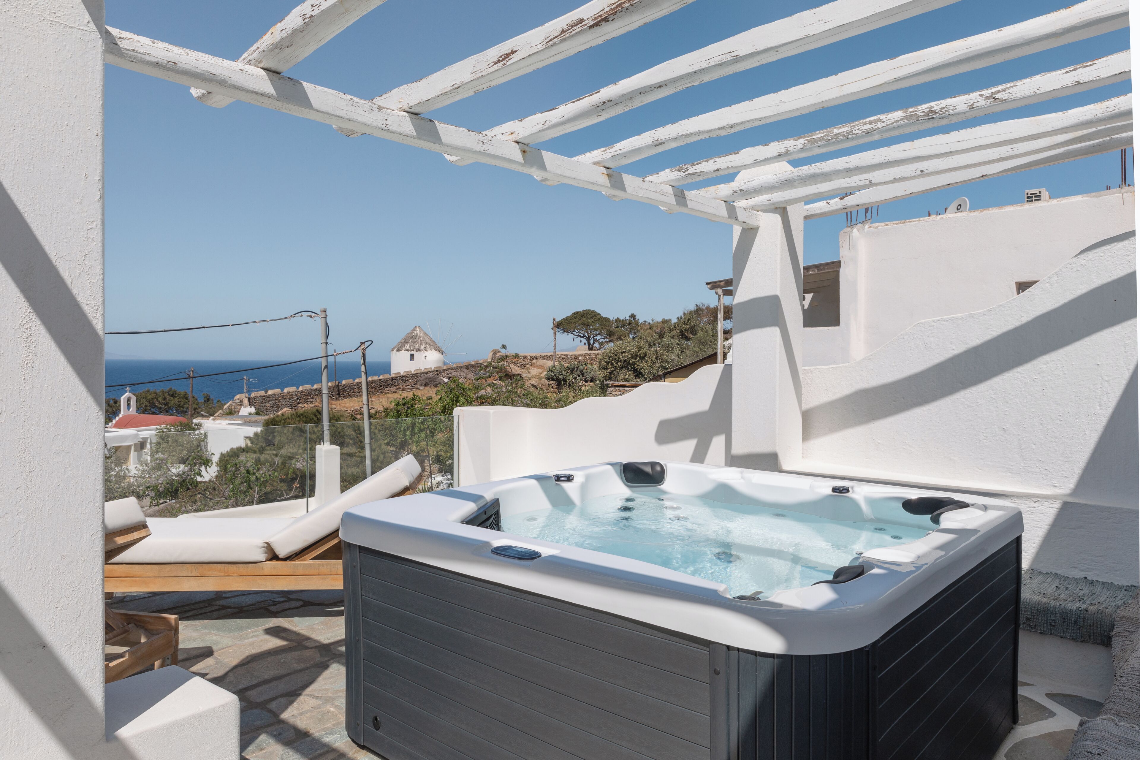 Een jacuzzi op een dak met uitzicht op zee en een wit gebouw op de achtergrond.