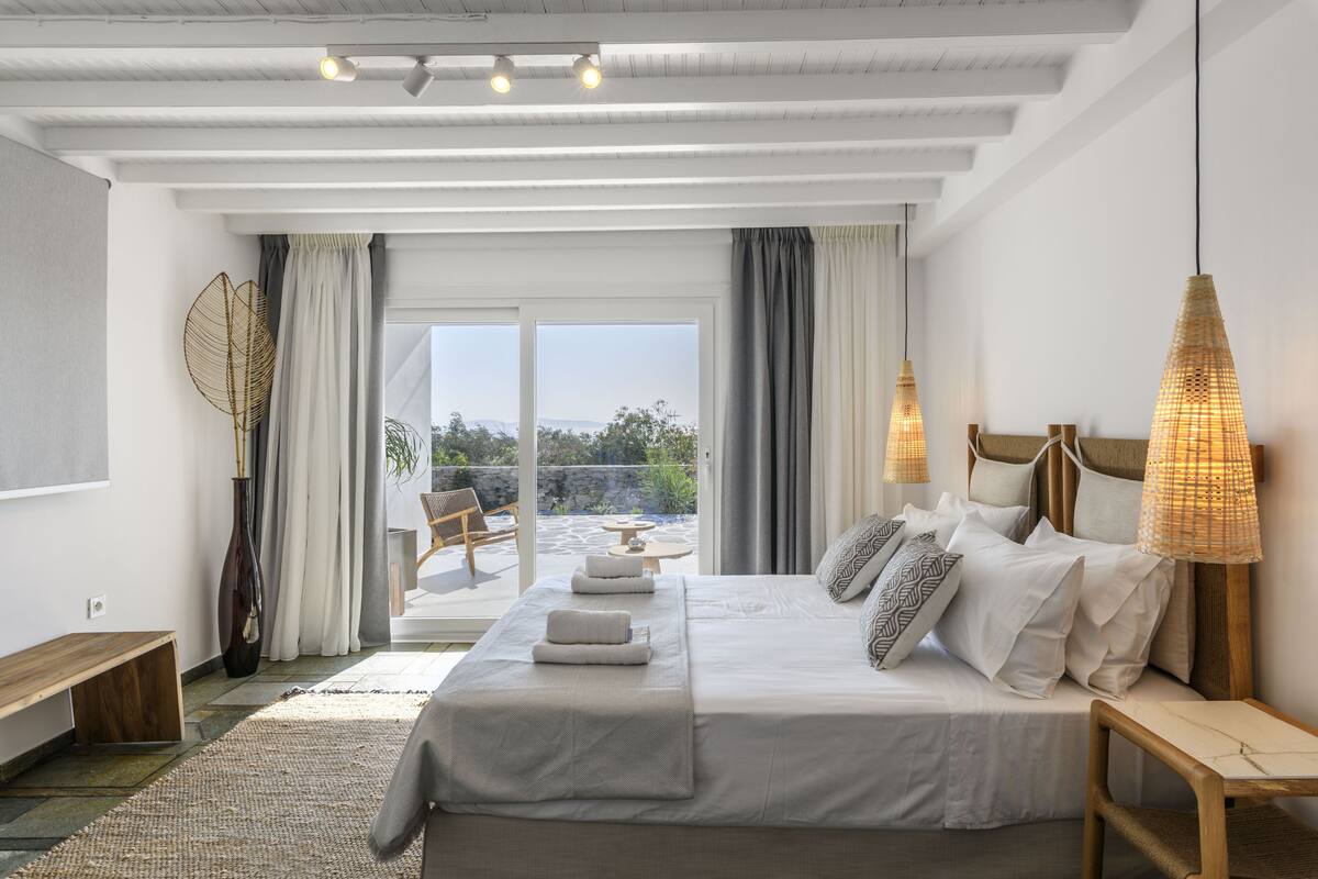 Un dormitorio moderno con una cama grande, lámparas de noche y vistas al exterior.
