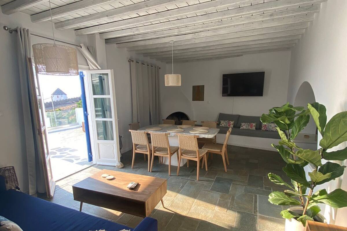 Una sala de estar acogedora con un sofá azul, una mesa de madera y un comedor con sillas.
