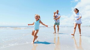 Escena de playa con una familia caminando sobre la arena.