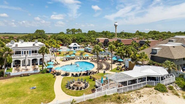 Un resort con piscina, mobiliario exterior y un edificio grande con terraza cubierta.