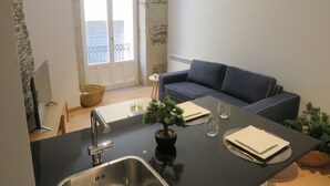 Una cocina compacta con un lavamanos, una pequeña mesa de comedor y un sofá azul.