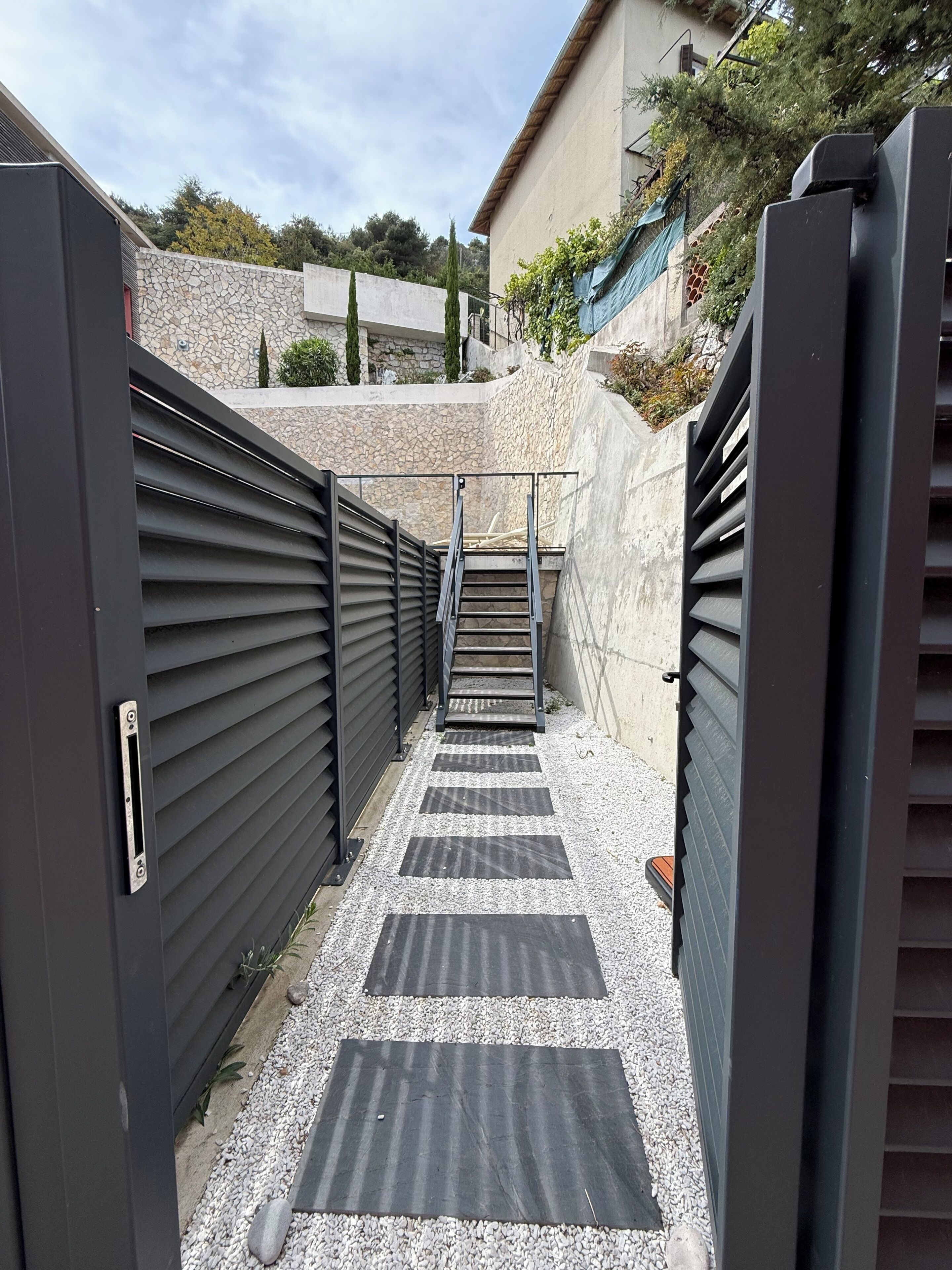 A gated entrance with a metal staircase leading to a stone wall.