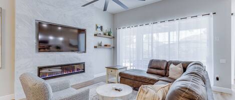 Una sala de estar moderna con chimenea, sofá de cuero y ventilador de techo.