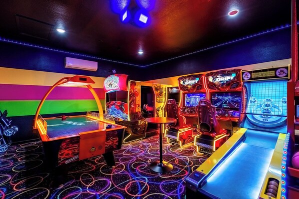 Un salón de juegos muy iluminado, con luces de neón y diversas máquinas recreativas.