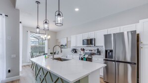Una cocina moderna con armarios blancos, electrodomésticos de acero inoxidable y una isla central.