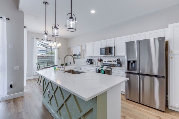 A modern kitchen with white cabinetry, stainless steel appliances, and a central island.