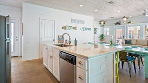 A modern kitchen with a central island, white cabinetry, and a view to the dining area.