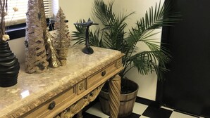 A checkered floor, a marble table with decorative items, and a potted plant.