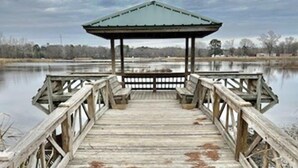 A wooden pier leading to a gazebo with benches.