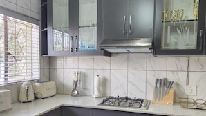 A modern kitchen with dark cabinets, a gas stove, a toaster, and a window with blinds.