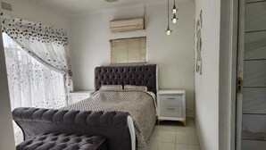 A bedroom with a bed, bedside tables, a wardrobe, and a window with curtains.