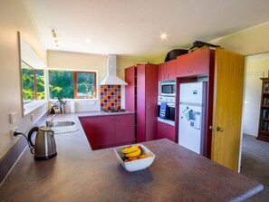 Eine moderne Küche mit einem großen Fenster, einem Herd, einer Mikrowelle und einem Kühlschrank.