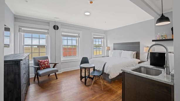 A modern bedroom with a bed, bedside table, and a built-in sink. - Historic Elegance Loft in Downtown Conway (Conway)