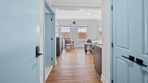 A hallway with light blue doors, wooden flooring, and a view to a dining area with a table and chairs. - Historic Elegance Loft in Downtown Conway (Conway)