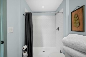 A bathroom with a shower, toilet, and a towel rack.