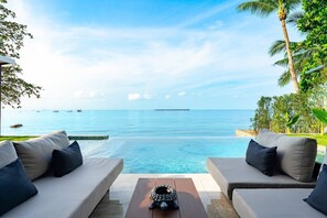 A poolside area with two sofas and a small table, overlooking a clear blue sea with boats in the distance. - Beachfront 4BR Sunset Villa w/ Staff & Saltwater Infinity Pool (Koh Samui)