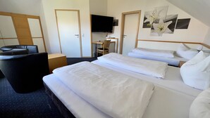 Una habitación de hotel con dos camas, un escritorio, una silla y un televisor.