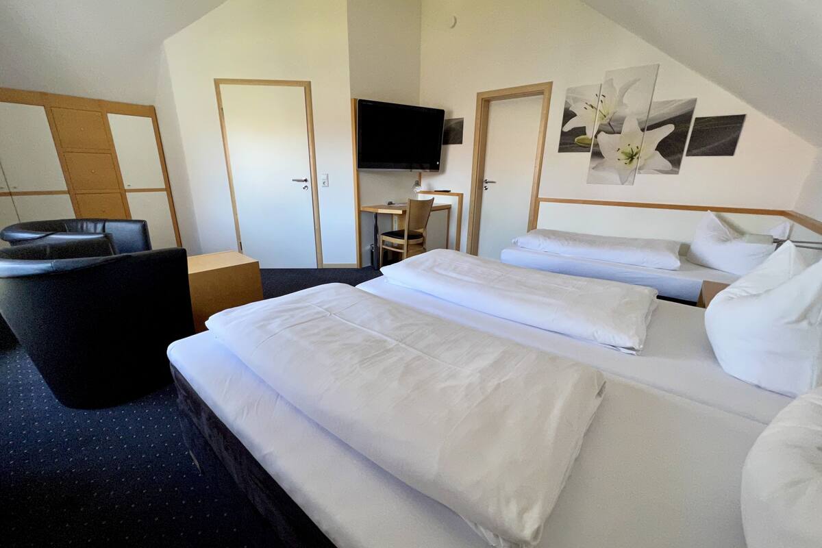 Ein Hotelzimmer mit zwei Betten, einem Schreibtisch, einem Stuhl und einem Fernseher.