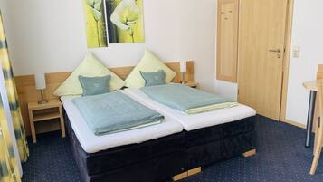 Ein Doppelbett mit zwei Kissen, ein Nachttisch mit Lampe und ein Holzschrank.