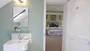 A bathroom with a white sink, mirror, and glass shelf. - Thistlebank Townhouse  (Whitby)
