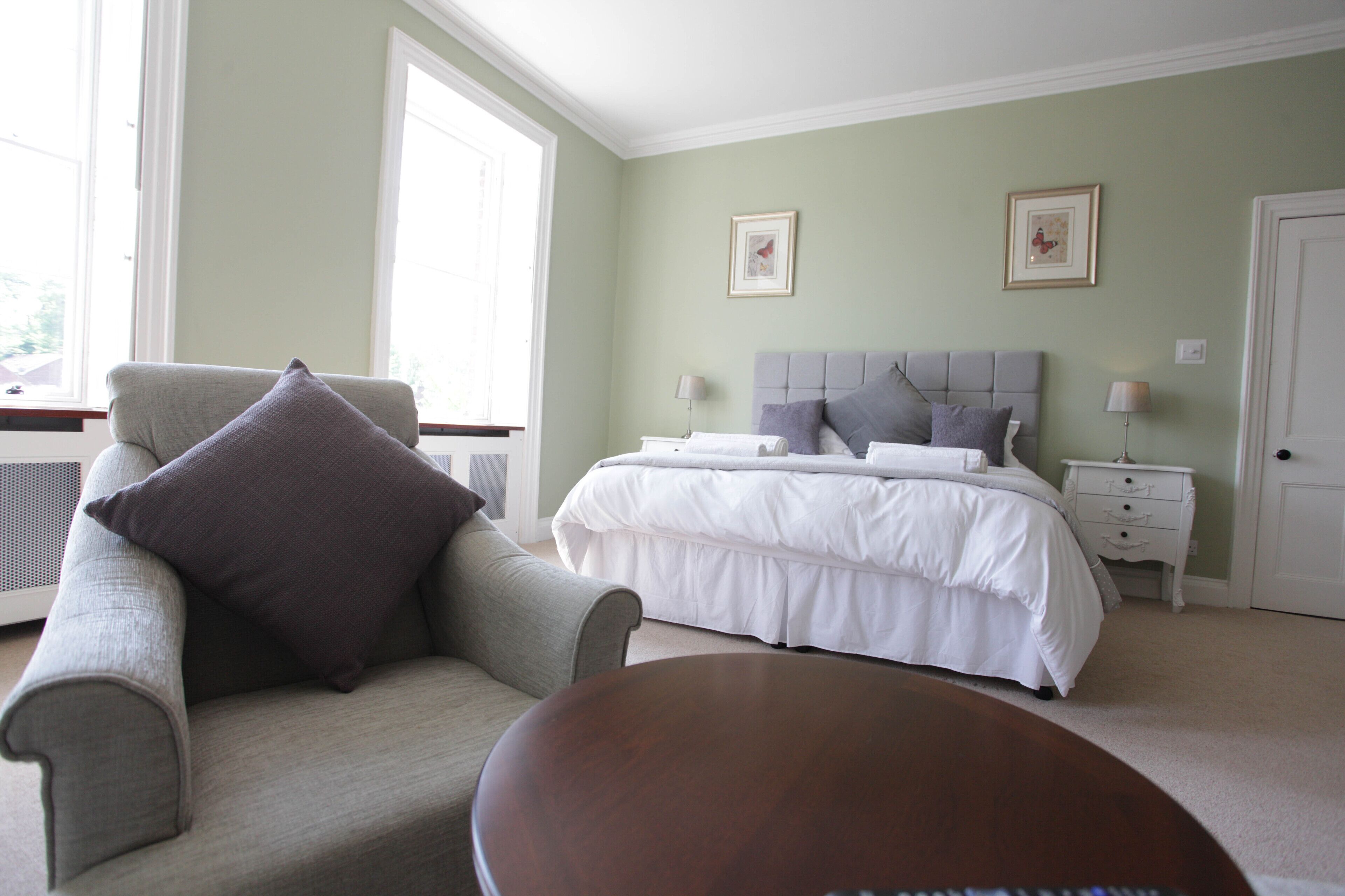 Une chambre à coucher avec un lit, une chaise, une table de chevet et une fenêtre.