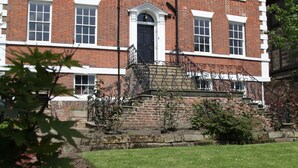 A red brick building with white window frames and a black door. - Thistlebank Townhouse  (Whitby)