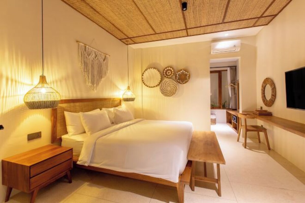 Un dormitorio con cama, mesita de noche, lámpara, decoración en la pared y un escritorio con silla.