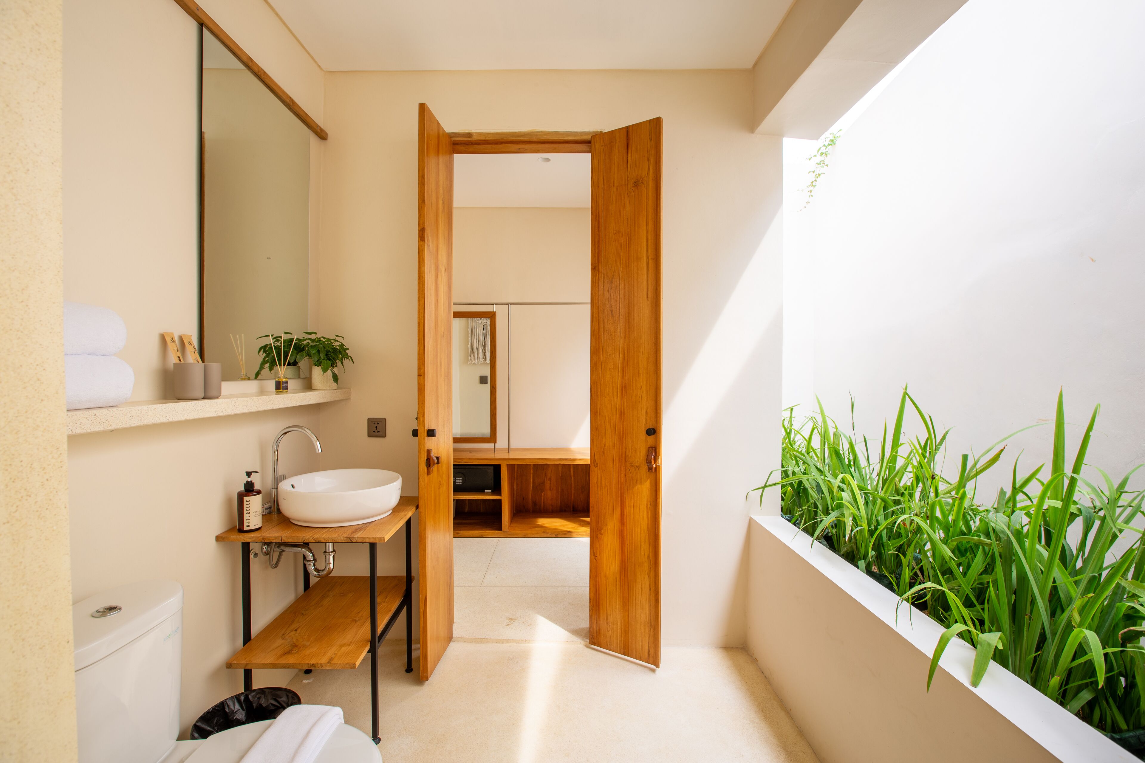 A modern bathroom with a wooden vanity, a white sink, and a mirror.