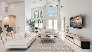 A modern living room with a white sofa, a coffee table, and a TV on a wooden stand. - Villa Rapa Nui Island (Cape Coral)