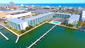 A modern hotel with a marina, featuring a long dock and multiple buildings with balconies.