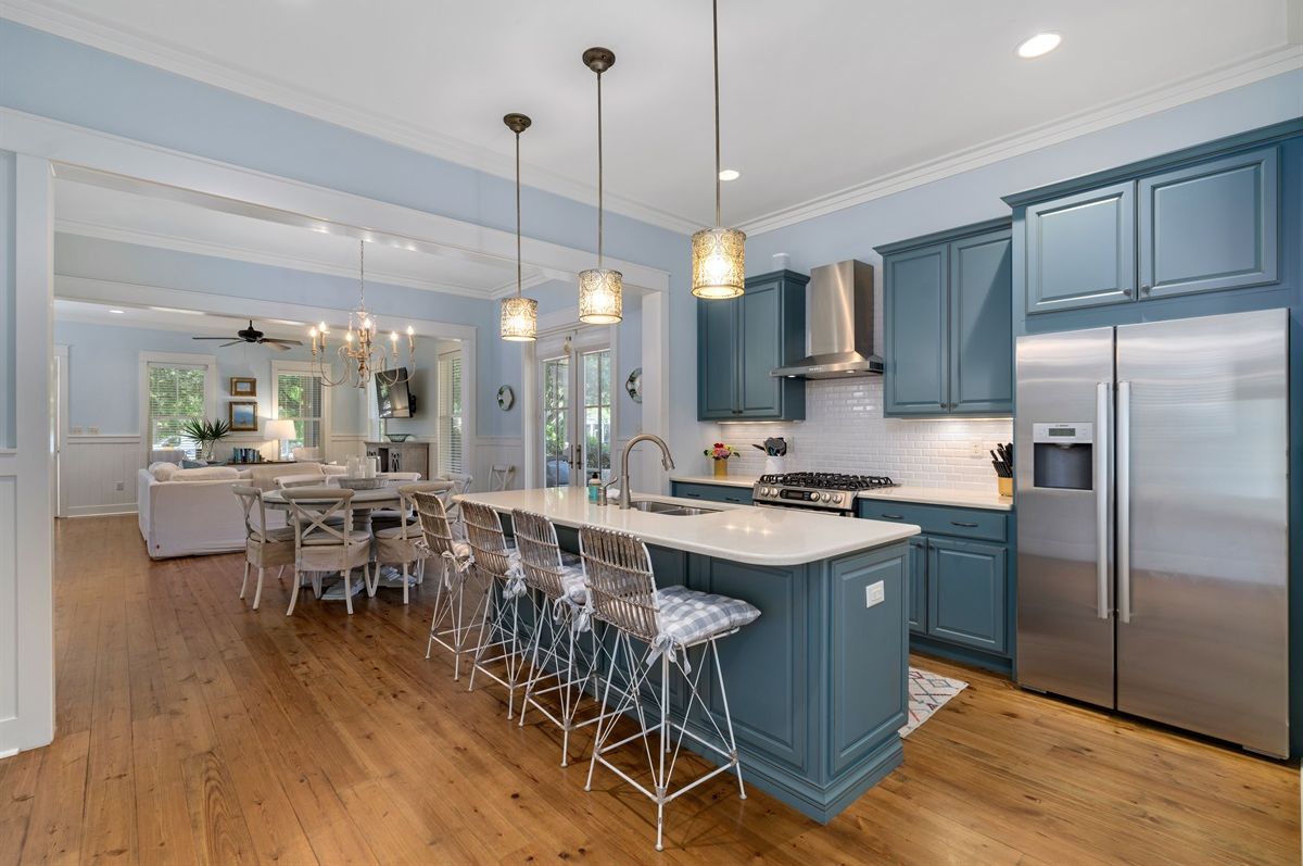 A modern kitchen with a central island, bar stools, and stainless steel appliances.
