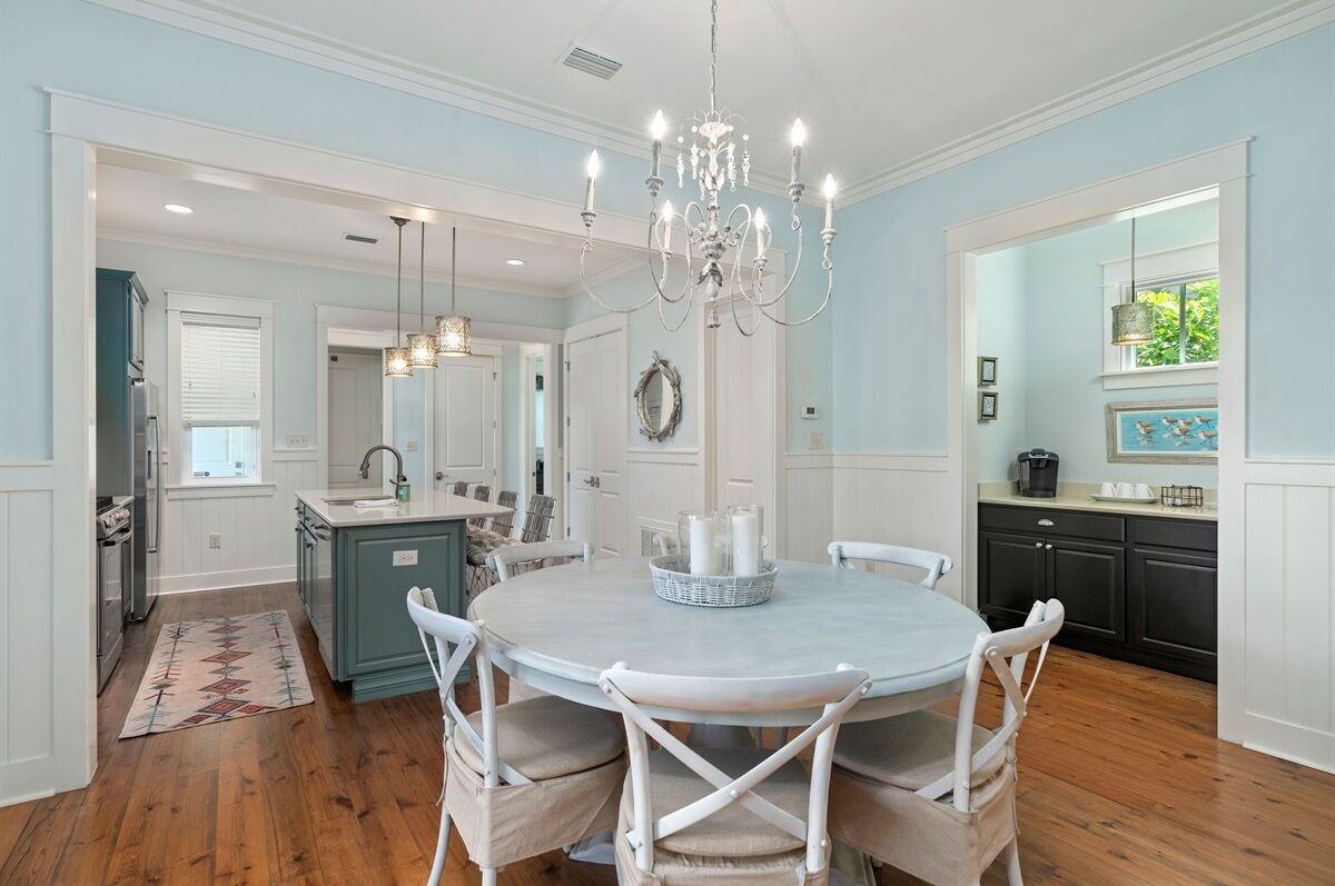 A spacious kitchen with a central island, white cabinetry, and a chandelier.