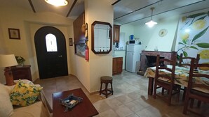 A living room with a sofa, a small table, a dining area with chairs, a kitchen with a refrigerator and microwave, and a fireplace. - Stunning 3-bed House in Gallinaro, Aircon and Pool (Gallinaro)