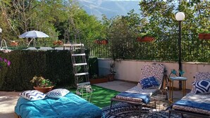 Une terrasse sur le toit aménagée avec un lit, des chaises longues et un tapis à motifs.